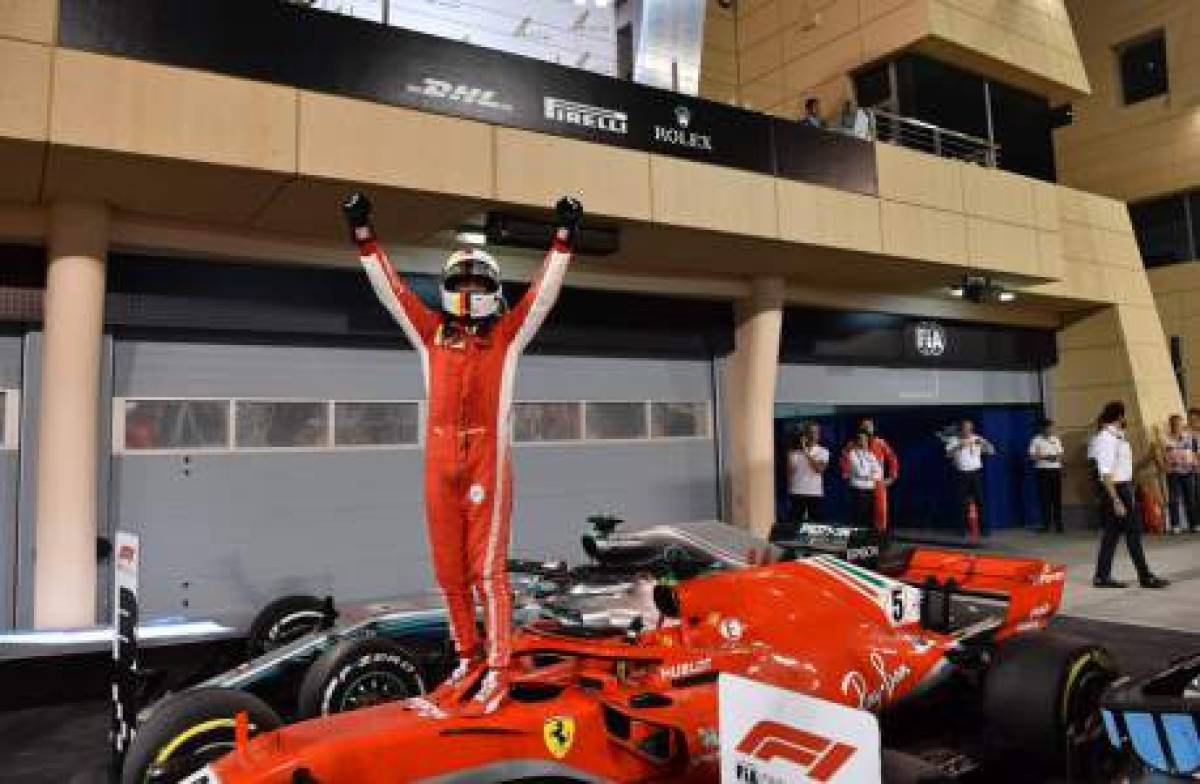 Ferrari's German driver Sebastian Vettel celebrates on his car in the winner's enclosure after winning the Bahrain Formula One Grand Prix at the Sakhir circuit in Manama on April 8, 2018. / AFP PHOTO / Andrej ISAKOVIC