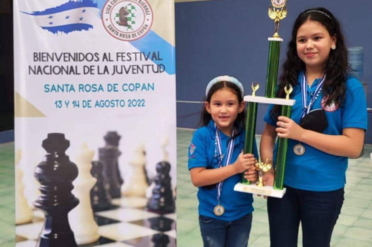 Ximena Bobadilla y Diana Bobadilla levantando el trofeo obtenido por su equipo en el torneo.