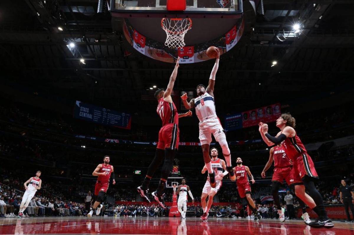 Jugadores de los Miami Heat interceptando una canasta.