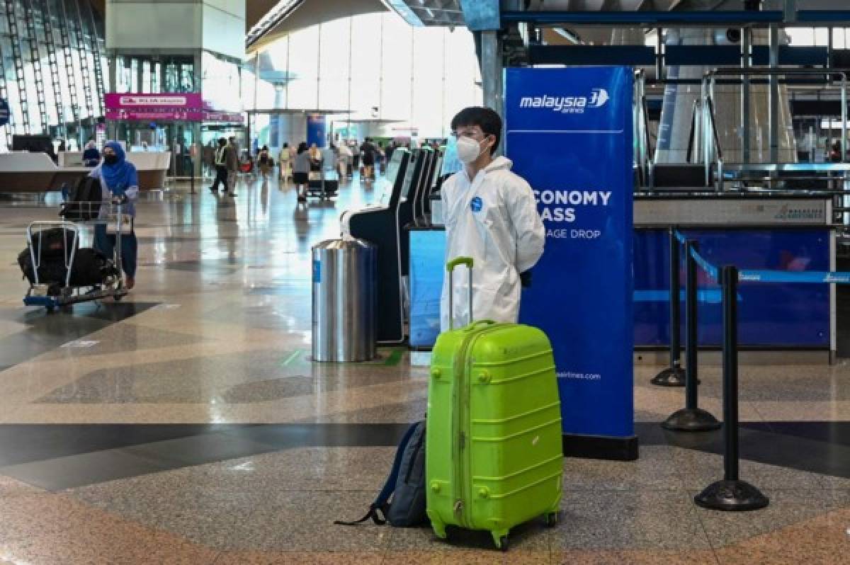 A passenger wearing personal protective equipment (PPE) stands by his luggage at the Kuala Lumpur International Airport (KLIA) in Sepang on November 29, 2021, as countries across the globe shut borders and renewed travel curbs in response to the spread of a new, heavily mutated Covid-19 coronavirus variation dubbed Omicron. (Photo by Mohd RASFAN / AFP)