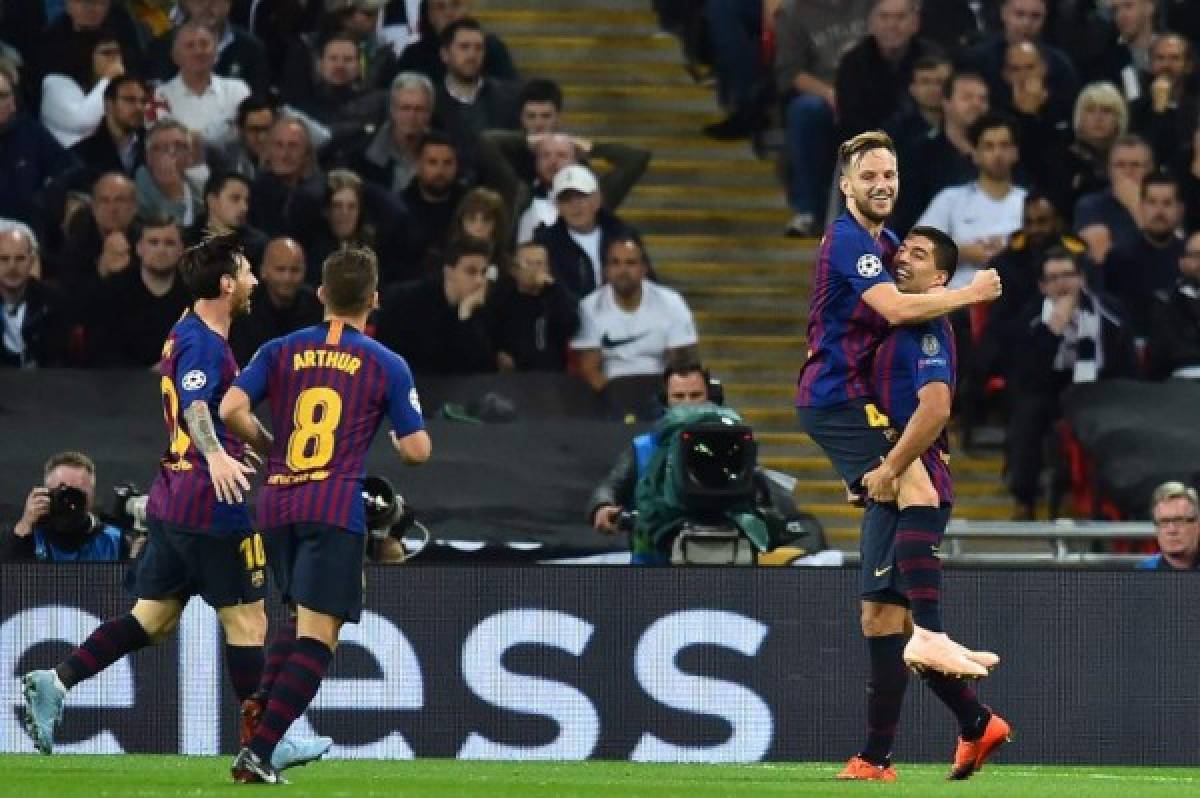 Barcelona's Croatian midfielder Ivan Rakitic (2nd R) leaps into the arms of Barcelona's Uruguayan striker Luis Suarez after scoring their second goal during the Champions League group B football match match between Tottenham Hotspur and Barcelona at Wembley Stadium in London, on October 3, 2018. / AFP PHOTO / Glyn KIRK