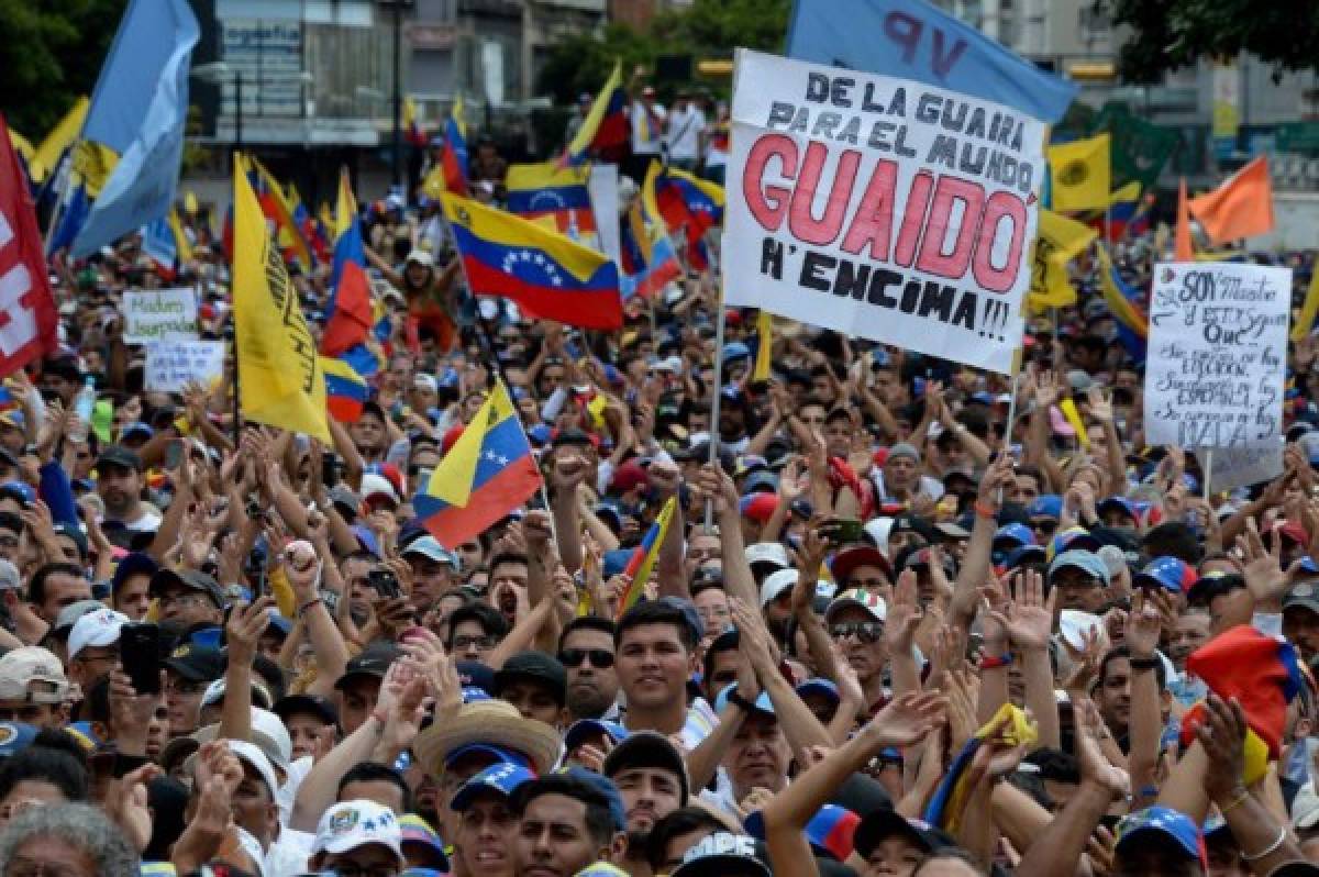 People cheer as they listen to Venezuela's National Assembly head Juan Guaido (out of frame) during a mass opposition rally against leader Nicolas Maduro in which he declared himself the country's 'acting president', on the anniversary of a 1958 uprising that overthrew military dictatorship, in Caracas on January 23, 2019. - 'I swear to formally assume the national executive powers as acting president of Venezuela to end the usurpation, (install) a transitional government and hold free elections,' said Guaido as thousands of supporters cheered. Moments earlier, the loyalist-dominated Supreme Court ordered a criminal investigation of the opposition-controlled legislature. (Photo by Federico PARRA / AFP)