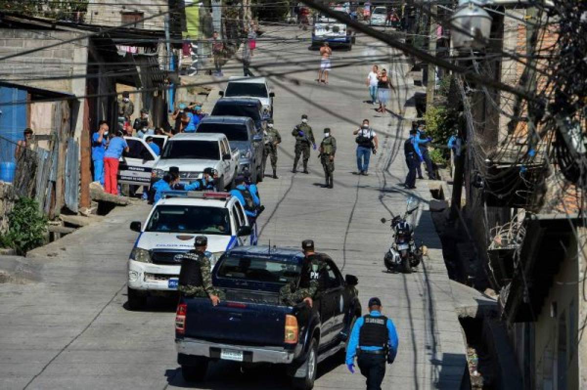 Soldiers and police officers assist Health personnel at the Abraham Lincoln colony in Tegucigalpa, on March 17, 2020 after two new cases of the new coronavirus, COVID-19 were confirmed. - The Honduran government decreed a curfew on Monday night 'to contain the advance of the coronavirus', confirming two new cases for a total of eight infected. (Photo by Orlando SIERRA / AFP)