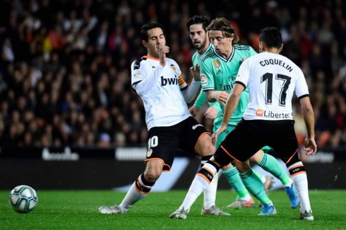 Real Madrid's Croatian midfielder Luka Modric (C) vies with Valencia's French midfielder Francis Coquelin (R) and Valencia's Spanish midfielder Daniel Parejo (L) during the Spanish League football match between Valencia CF and Real Madrid, at the Mestalla stadium in Valencia, on December 15, 2019. (Photo by JOSE JORDAN / AFP)