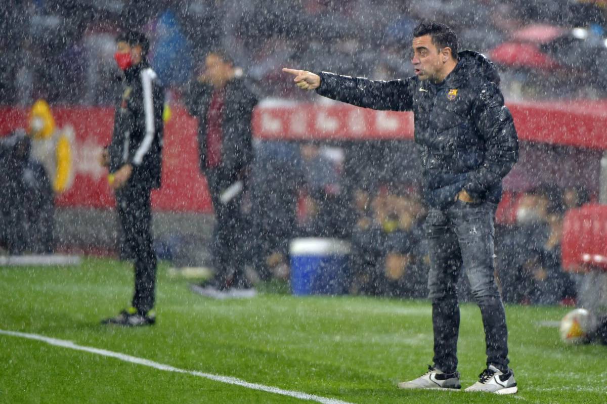Xavi empapado de agua dirigiendo a su equipo ante el Sevilla, la tormenta es muy fuerte. (FOTO: AFP)