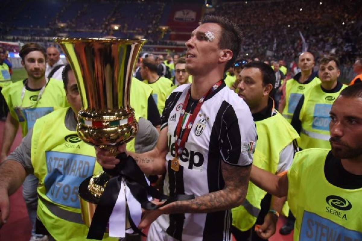 Juventus' forward from Croatia Mario Mandzukic holds the trophy after winning the Italian Tim Cup final on May 17, 2017 at the Olympic stadium in Rome. Dani Alves and Leonardo Bonucci struck one apiece as treble-chasing Juventus secured a third successive Italian Cup with a 2-0 victory over Lazio at the Stadio Olimpico today.Juventus, who won a league and Cup double the past two seasons, can clinch a record sixth consecutive Serie A title -- and a record third successive double -- with victory at home to Crotone in their penultimate Serie A game of the season on Sunday. / AFP PHOTO / FILIPPO MONTEFORTE