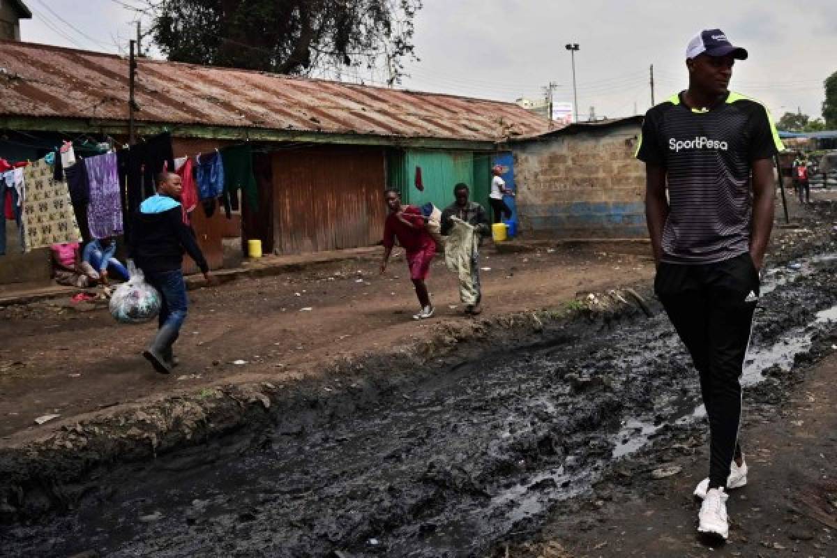 (FILES) In this file photo taken on June 13, 2019 Harrison Osotsi strolls through ramshackle Muthurwa neighbourhood in Nairobi. - Harrison Osotsi and younger bother Eli are both cousins of English Premier League Club Totenham Hotspurs' midfielder Victor Wanyama who grew up in this place, honing his football skills among the rows of single-room units to become a local icon for the game aspirants and enthusiasts. (Photo by TONY KARUMBA / AFP)