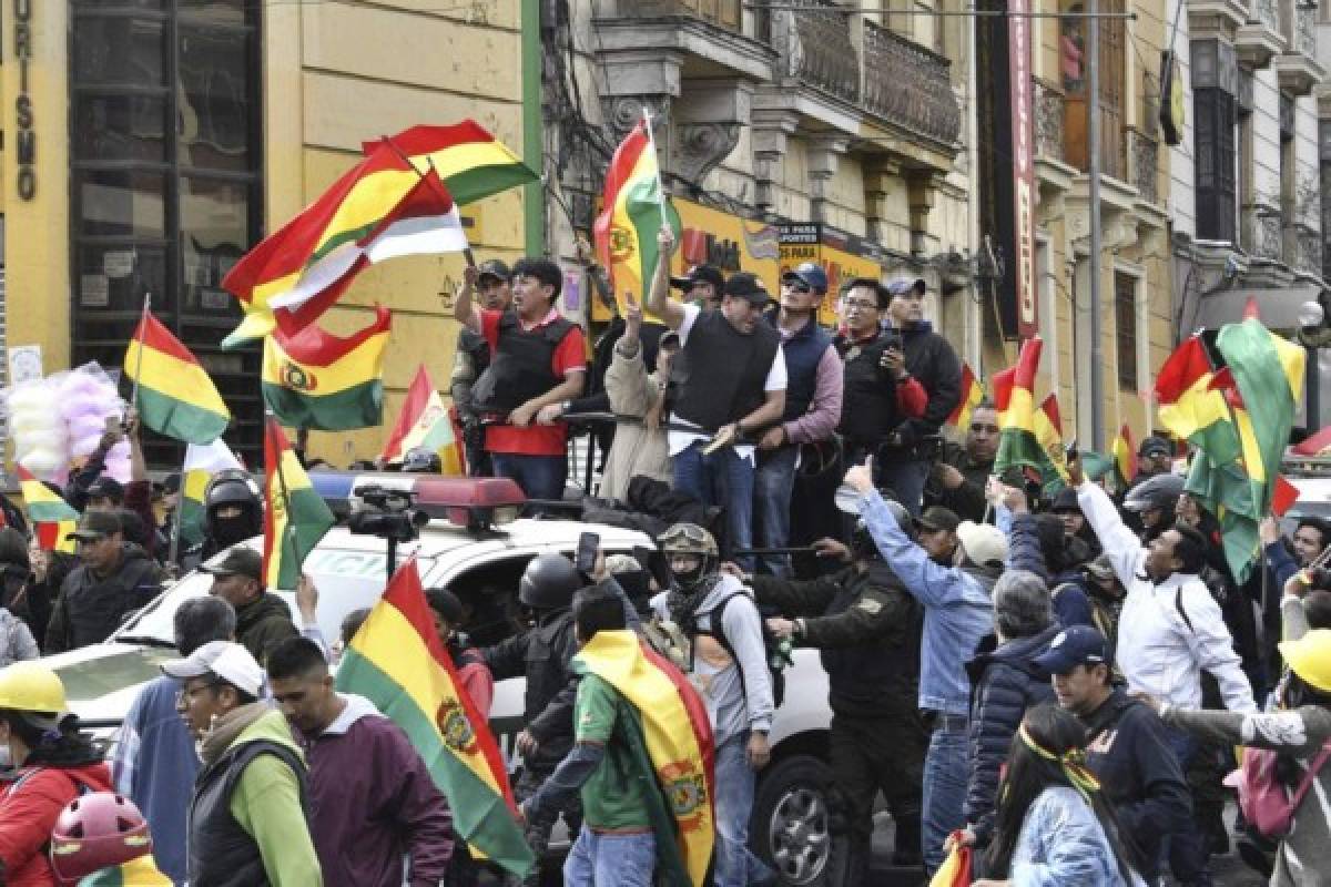 Luis Fernando Camacho (C), a Bolivian opposition leader, waves a Bolivian national flag in La Paz on November 10, 2019 after delivering a letter to Bolivia's President Evo Morales demanding his resignation. - Bolivian President Evo Morales announced his resignation Sunday, caving in following three weeks of sometimes-violent protests over his disputed re-election after the army and police withdrew their backing. (Photo by AIZAR RALDES / AFP)