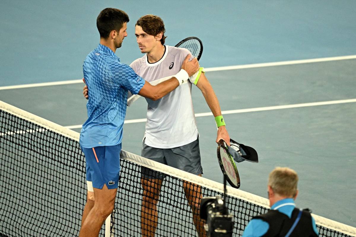 El serbio Novak Djokovic abraza al australiano Alex De Minaur después de su partido individual masculino en el octavo día del Abierto de Australia.
