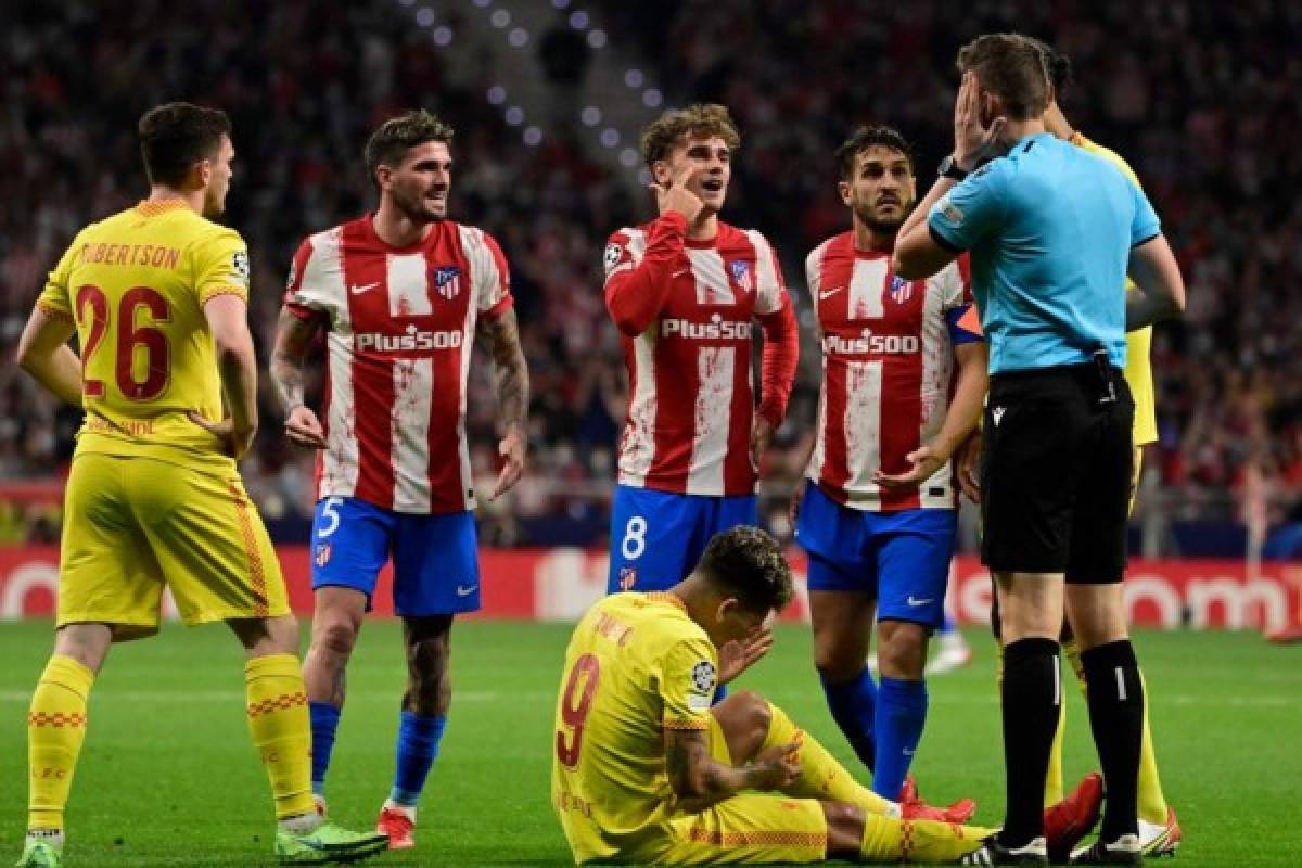 Liverpool's Brazilian forward Roberto Firmino lies on the ground as Atletico Madrid's French forward Antoine Griezmann talks to German referee Daniel Siebert after receiving a red card, during the UEFA Champions League Group B football match between Atletico Madrid and Liverpool at the Wanda Metropolitano stadium in Madrid on October 19, 2021. (Photo by JAVIER SORIANO / AFP)
