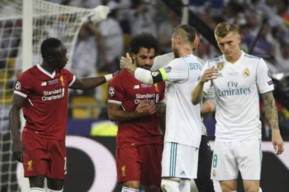 Real Madrid's Spanish defender Sergio Ramos (2nd R) comes over to console Liverpool's Egyptian forward Mohamed Salah (2nd L) who has been forced the leave the pitch after hurting his shoulder in a challenge with Sergio Ramos during the UEFA Champions League final football match between Liverpool and Real Madrid at the Olympic Stadium in Kiev, Ukraine on May 26, 2018. / AFP PHOTO / Paul ELLIS