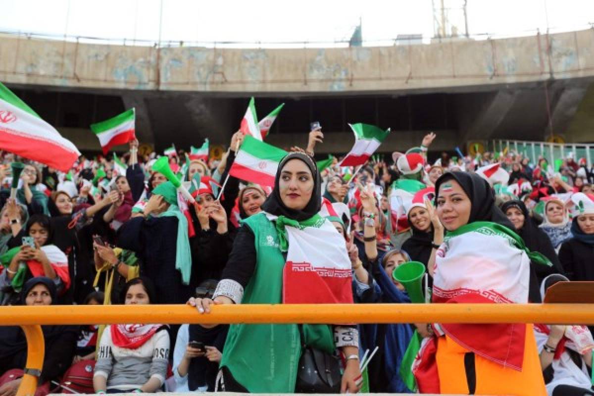 Iranian women cheer during the World Cup Qatar 2022 Group C qualification football match between Iran and Cambodia at the Azadi stadium in the capital Tehran on October 10, 2019. - The Islamic republic has barred female spectators from football and other stadiums for around 40 years, with clerics arguing they must be shielded from the masculine atmosphere and sight of semi-clad men. Women fans are attending the football match freely for the first time in decades, after FIFA threatened to suspend the country over its controversial male-only policy. (Photo by ATTA KENARE / AFP)