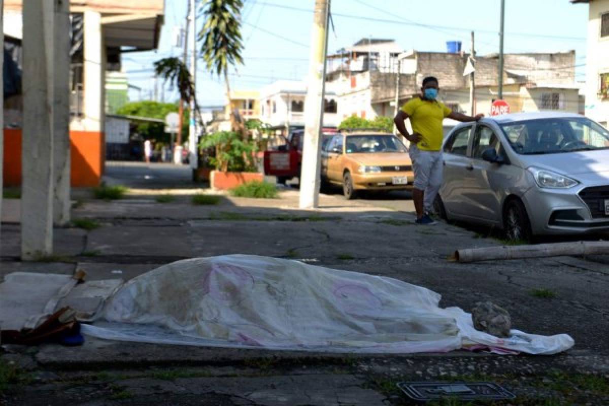 A man looks at a body said to be laying for three days oustide a clinic in Guayaquil, Ecuador on April 3, 2020. - Troops and police in Ecuador have collected at least 150 bodies from streets and homes in the country's most populous city Guayaquil amid warnings that as many as 3,500 people could die of the COVID-19 coronavirus in the city and surrounding province in the coming months. (Photo by Str / Marcos Pin / AFP)