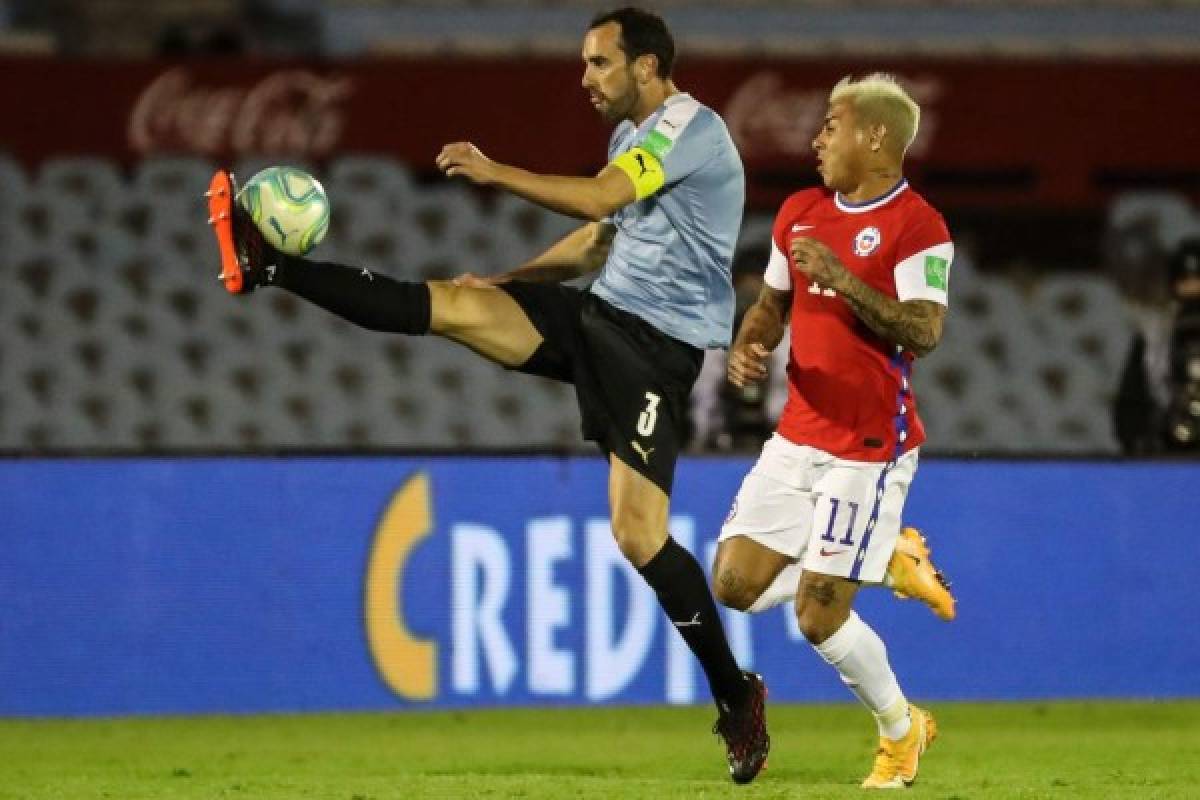 Uruguay's Diego Godin (L) strikes the ball next to Chile's Eduardo Vargas during their 2022 FIFA World Cup South American qualifier football match at the Centenario Stadium in Montevideo on October 8, 2020, amid the COVID-19 novel coronavirus pandemic. (Photo by Raul MARTINEZ / various sources / AFP)