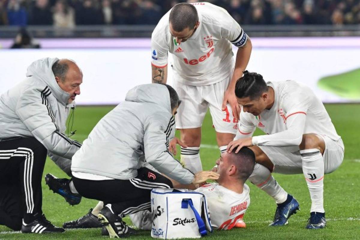 Staff medics (L), Juventus' Italian defender Leonardo Bonucci (Top) and Juventus' Portuguese forward Cristiano Ronaldo (R) tend to Juventus' Turkish defender Merih Demiral after he was injured during the Italian Serie A football match AS Roma vs Juventus on January 12, 2020 at the Olympic stadium in Rome. (Photo by Tiziana FABI / AFP)