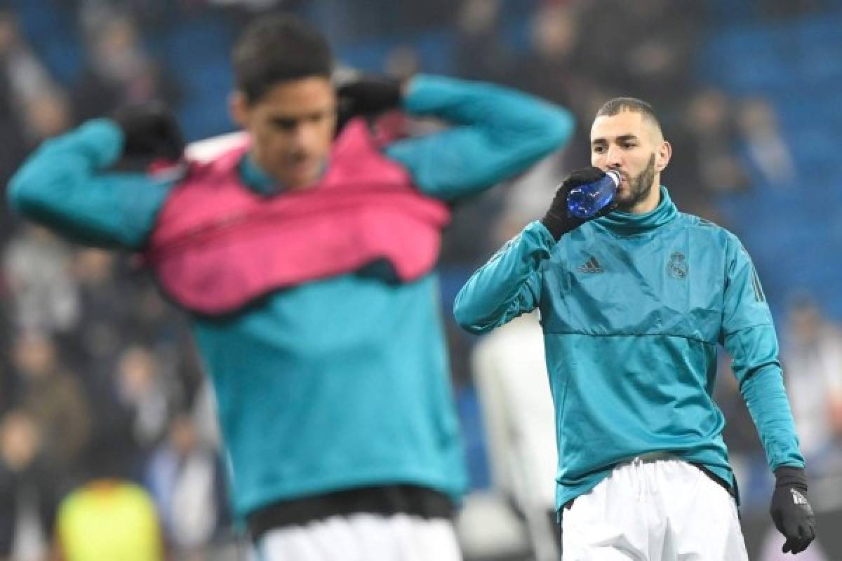 Real Madrid's French forward Karim Benzema (R) and Real Madrid's French defender Raphael Varane warm up before the UEFA Champions League round of sixteen first leg football match Real Madrid CF against Paris Saint-Germain (PSG) at the Santiago Bernabeu stadium in Madrid on February 14, 2018. / AFP PHOTO / GABRIEL BOUYS