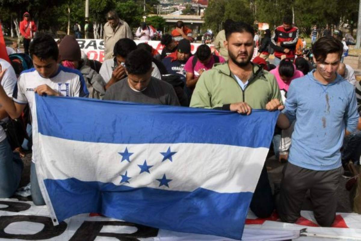 Supporters of Honduran presidential candidate for the Opposition Alliance against the Dictatorship party Salvador Nasralla, kneel to pray during a protest near the Electoral Supreme Court (TSE), to demand the announcement of the election final results in Tegucigalpa, on November 30, 2017. Honduran opposition candidate Salvador Nasralla said he would not recognize the results to be announced by the Supreme Electoral Tribunal, after accusing it of tampering with the vote count to favor the reelection of President Juan Orlando Hernandez. / AFP PHOTO / ORLANDO SIERRA