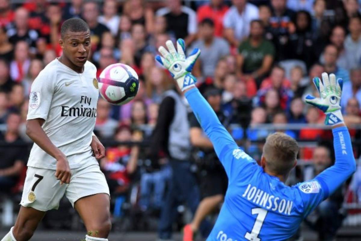 Paris Saint-Germain's French forward Kylian Mbappe (L) scores to Guingamp's Swedish goalkeeper Karl-Johan Johnsson during the French L1 football match between Guingamp and Paris Saint-Germain, at the Roudourou stadium in Guingamp on August 18, 2018. / AFP PHOTO / LOIC VENANCE