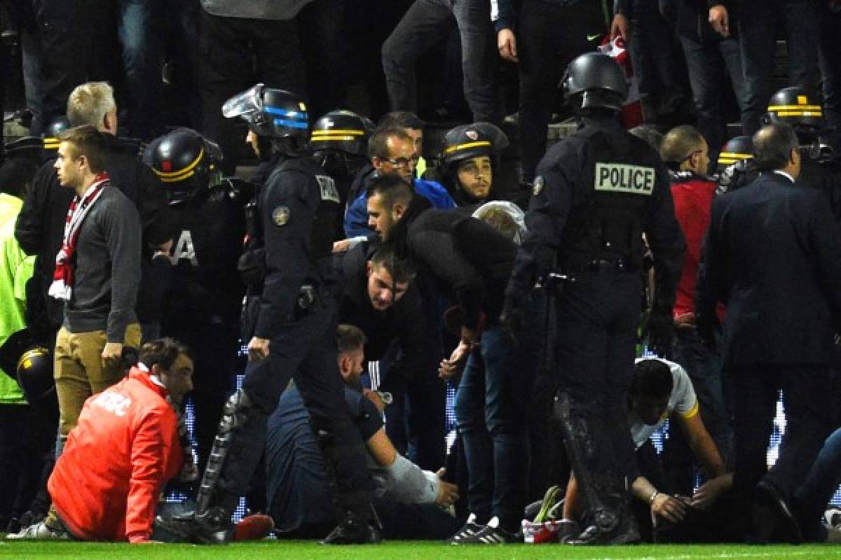 French police officers and members of the stadium staff gather to help LOSC's supporters following the fall of their tribune during the French L1 football match between Amiens and Lille LOSC on September 30, 2017 at the Licorne stadium in Amiens.Several Lille supporters were hurt in Amiens when a stadium barrier collapsed in the away section as the visiting fans celebrated the opening goal of the match. The Ligue 1 fixture was interrupted in the 16th minute after Fode Ballo-Toure's goal sparked celebrations that caused a fence separating the fans from the pitch to crumble under their weight. Dozens of fans tumbled down on to the side of the pitch, crushed by fellow supporters, with medical staff quickly rushing to the scene to tend to those injured. / AFP PHOTO / FRANCOIS LO PRESTI