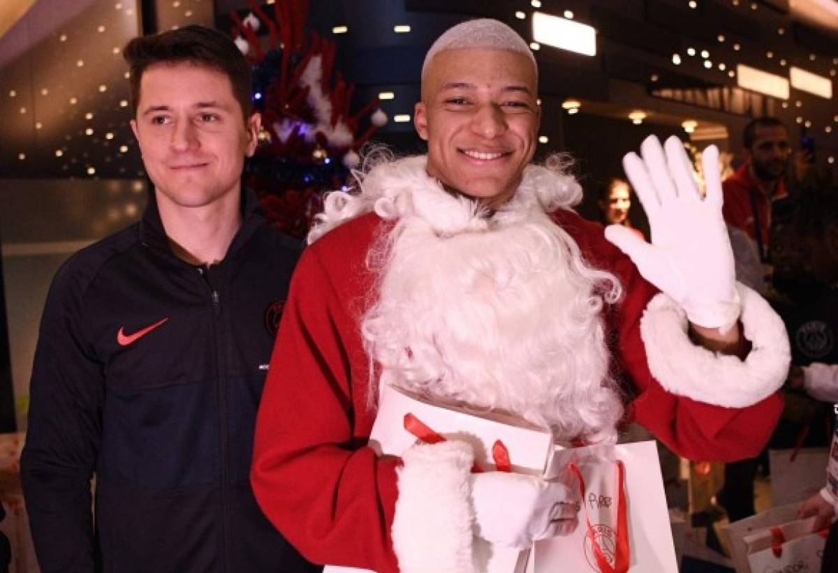 TOPSHOT - Paris Saint-Germain's Spanish midfielder Ander Herrera (L) and Paris Saint-Germain's French forward Kylian MBappe dressed as Santa Claus pose for a picture as they give gifts to children from the Paris Saint-Germain's foundation after the French Ligue 1 football match between Paris Saint-Germain (PSG) and Amiens SC (ASC) at the Parc des Princes stadium in Paris on December 21, 2019. (Photo by FRANCK FIFE / AFP)