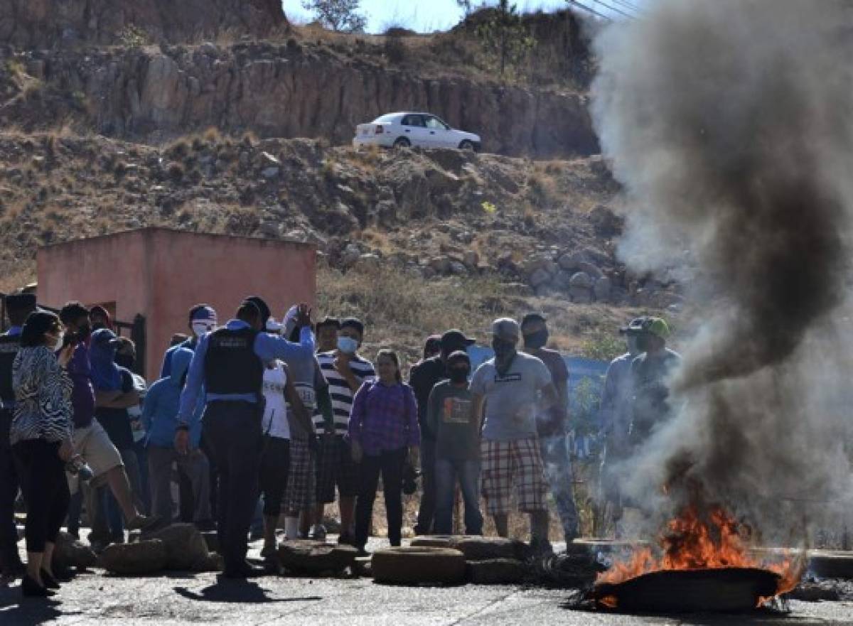 Demonstrators with their faces covered against the spread of the new coronavirus, block a street demanding the government for food in Tegiucigalpa on March 31, 2020, after the curfew was extended for two more weeks. - 141 cases of COVID-19 were registered so far in the Central American nation. (Photo by ORLANDO SIERRA / AFP)