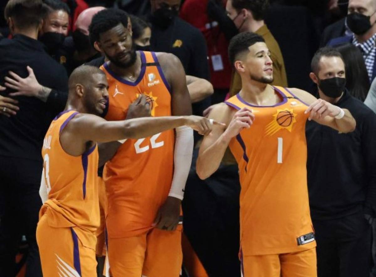 LOS ANGELES, CALIFORNIA - JUNE 30: Devin Booker #1 of the Phoenix Suns celebrates with teammates Deandre Ayton #22 and Chris Paul #3 following the team's series win against the LA Clippers in Game Six of the Western Conference Finals at Staples Center on June 30, 2021 in Los Angeles, California. NOTE TO USER: User expressly acknowledges and agrees that, by downloading and or using this photograph, User is consenting to the terms and conditions of the Getty Images License Agreement. Harry How/Getty Images/AFP (Photo by Harry How / GETTY IMAGES NORTH AMERICA / Getty Images via AFP)