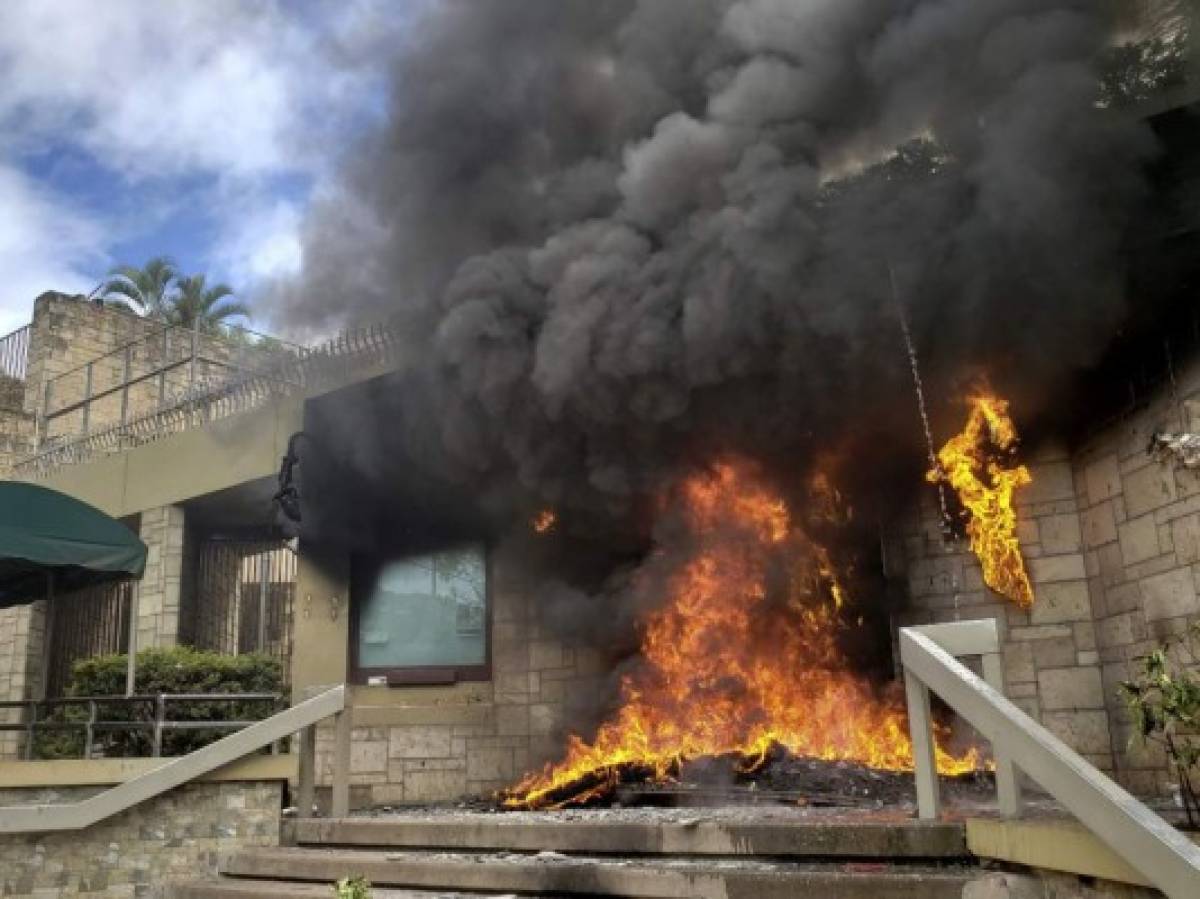 The entrance of the US embassy in Tegucigalpa burns after being set on fire by demonstrators of the education and health sectors protesting against government reforms, on May 31, 2019. - Thousands of teachers, doctors and students resumed their protests against government measures that thay say will privatize health and education services. (Photo by Orlando SIERRA / AFP)