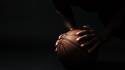 Cropped photo of afro american basketball player, doing pushup exercise on the ball, on black background