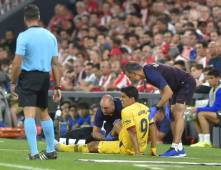 El delantero Luis Suárez sobre el césped siendo atendido por el cuerpo técnico.
