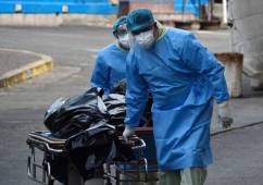 Health workers carry the bodies of two victims of COVID-19 on trolleys outside an improvised tent mounted at the state Escuela Hospital in Tegucigalpa on June 15, 2020 amid the novel coronavirus pandemic. - Health authorities in Honduras have been forced to mount four tents to treat patients, as rooms -including those for patients with other illnesses- are at full capacity. Honduras has reported at least 323 deaths from COVID-19 so far. (Photo by Orlando SIERRA / AFP)