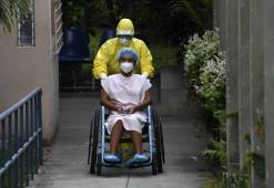 A health worker pushes the wheelchair of a 16-year-old patient infected with the new coronavirus who was in intensive care and recovered, as she is released from the San Rafael Hospital in Santa Tecla, El Salvador, on April 30, 2020. - Salvadorean President Nayib Bukele announced on Tuesday the extension of the mandatory isolation to combat the spread of COVID-19 until May 16. (Photo by Yuri CORTEZ / AFP)