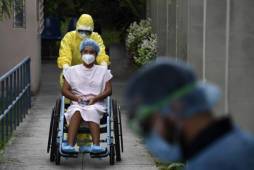 A health worker pushes the wheelchair of a 16-year-old patient infected with the new coronavirus who was in intensive care and recovered, as she is released from the San Rafael Hospital in Santa Tecla, El Salvador, on April 30, 2020. - Salvadorean President Nayib Bukele announced on Tuesday the extension of the mandatory isolation to combat the spread of COVID-19 until May 16. (Photo by Yuri CORTEZ / AFP)