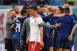 Poland's forward Robert Lewandowski walks past Slovakia's players celebrating their win after the UEFA EURO 2020 Group E football match between Poland and Slovakia at the Saint Petersburg Stadium in Saint Petersburg on June 14, 2021. (Photo by Kirill KUDRYAVTSEV / POOL / AFP)
