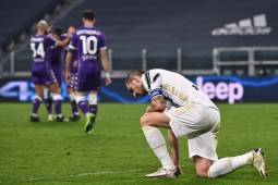 Juventus' Italian defender Leonardo Bonucci (R) reacts as Fiorentina's players celebrate (Rear L) after Juventus scored an own goal during the Italian Serie A football match Juventus vs Fiorentina on December 22, 2020 at the Juventus stadium in Turin. (Photo by Marco BERTORELLO / AFP)