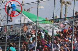 Momento en el que aficionado del Olimpia se sube a la malla para desatar la bandera que habían instalado los seguidores del Platense. Fotos Delmer Martínez