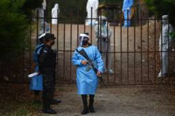 Honduran army soldiers stand guard at the Jardin de los Angeles Cemetery entrance where Municipality and Public Ministry workers prepare to burry COVID-19 victims, 14 kilometres northern Tegucigalpa, on May 14, 2020. (Photo by ORLANDO SIERRA / AFP)