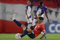 El hondureño Carlos Fernández del Fénix de Uruguay disputa la pelota con el chileno Pedro Hernández del Independiente quien se cae en la acción. Foto AFP