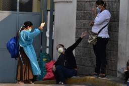 Women chat wearing face masks outside the Escuela Universitario Hospital (UNAH), where severe patients with the novel COVID-19 coronavirus will be attended in Tegucigalpa, on April 3, 2020. - Latin America is heading into 'a deep recession' in 2020, with an expected drop in the region's GDP of 1.8 to 4.0 percent due to the coronavirus pandemic, the UN economic commission for the region said Friday. (Photo by ORLANDO SIERRA / AFP)