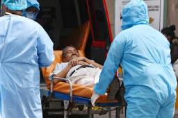 Una persona contagiada de coronavirus es trasladada por el personal de salud en el hospital Escuela de Tegucigalpa. Foto AFP