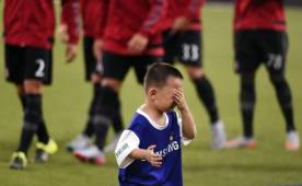 Un niño recogepelotas llora después de posar con los jugadores del Real Madrid (frente a jugadores de AC Milan).
