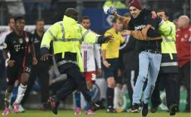 Personal de seguridad en el momento que lograban controlar al aficionado que invadió la cancha durante el duelo Bayern-Hamburgo en Alemania.
