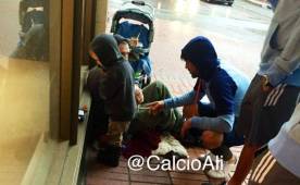 David Villa mientras habla y entrega comida a un hombre junto a su hijo que pedían limosna.