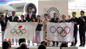 El gobernador de Tokio, Yuriko Koike (5º dcha), saluda mientras posa con la bandera olímpica y con la bandera del Comité Olímpico japonés.