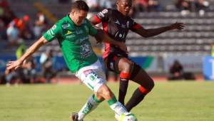 Félix Crisanto disputa la posesión de la pelota con Ramiro González, del León. FOTO: AFP