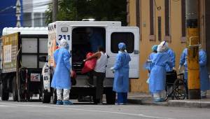 Una persona es ingresada a una ambulancia por miembros del Ministerio de Salud debido a los síntomas que sufría debido al coronavirus. Fotos AFP