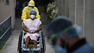 A health worker pushes the wheelchair of a 16-year-old patient infected with the new coronavirus who was in intensive care and recovered, as she is released from the San Rafael Hospital in Santa Tecla, El Salvador, on April 30, 2020. - Salvadorean President Nayib Bukele announced on Tuesday the extension of the mandatory isolation to combat the spread of COVID-19 until May 16. (Photo by Yuri CORTEZ / AFP)