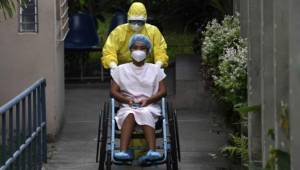 A health worker pushes the wheelchair of a 16-year-old patient infected with the new coronavirus who was in intensive care and recovered, as she is released from the San Rafael Hospital in Santa Tecla, El Salvador, on April 30, 2020. - Salvadorean President Nayib Bukele announced on Tuesday the extension of the mandatory isolation to combat the spread of COVID-19 until May 16. (Photo by Yuri CORTEZ / AFP)