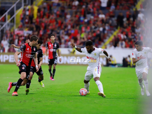 Jorge Benguché intenta quitarse dos marcas del Atlas en el Estadio Jalisco de Guadalajara.