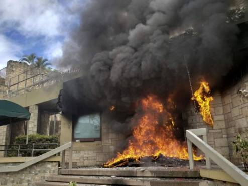 The entrance of the US embassy in Tegucigalpa burns after being set on fire by demonstrators of the education and health sectors protesting against government reforms, on May 31, 2019. - Thousands of teachers, doctors and students resumed their protests against government measures that thay say will privatize health and education services. (Photo by Orlando SIERRA / AFP)