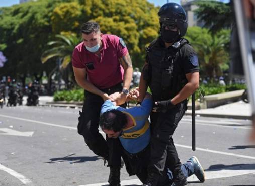 Photo released by Telam of a fan of Argentinian late football legend Diego Armando Maradona being arrested outside Casa Rosada presidential palace during disturbs as Maradona's wake takes place inside, in Buenos Aires, on November 26, 2020. - Argentine football legend Diego Maradona will be buried Thursday on the outskirts of Buenos Aires, a spokesman said. Maradona, who died of a heart attack Wednesday at the age of 60, will be laid to rest in the Jardin de Paz cemetery, where his parents were also buried, Sebastian Sanchi told AFP. (Photo by Ramiro GOMEZ / TELAM / AFP) / Argentina OUT / RESTRICTED TO EDITORIAL USE - MANDATORY CREDIT 'AFP PHOTO / TELAM / RAMIRO GOMEZ' - NO MARKETING - NO ADVERTISING CAMPAIGNS